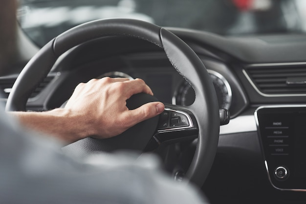Close-up of a man’s hands gripping the steering wheel while driving